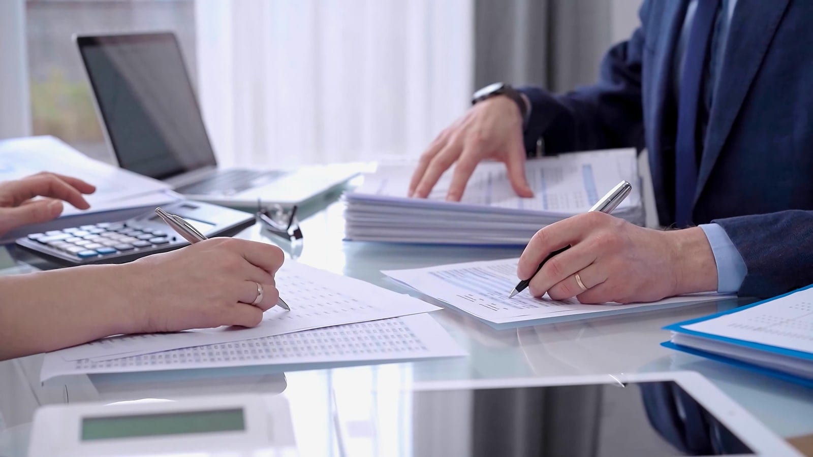 Two people reviewing and signing construction paperwork at a desk
